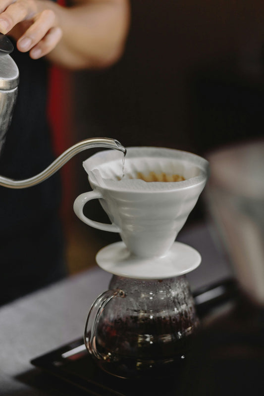 Versement d'eau chaude sur du café moulu dans une cafetière filtre