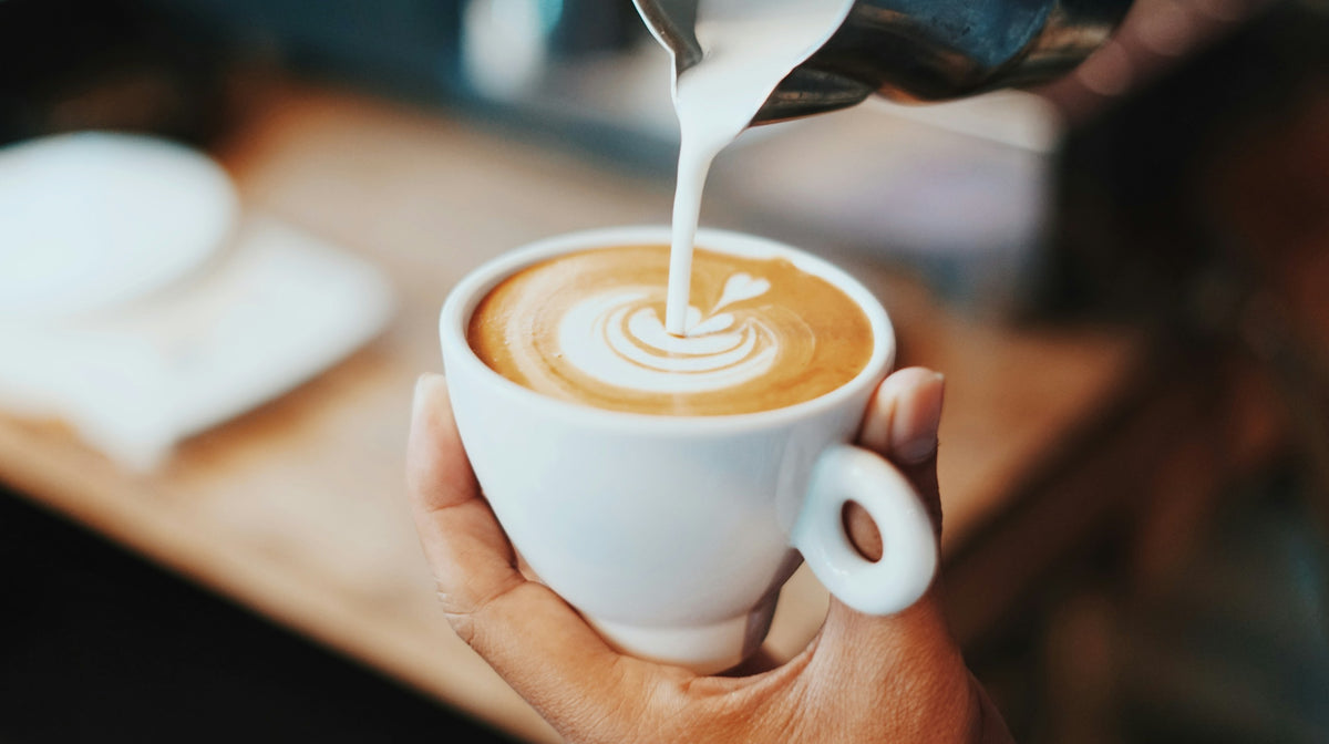 Barista versant un latte art dans une tasse de café