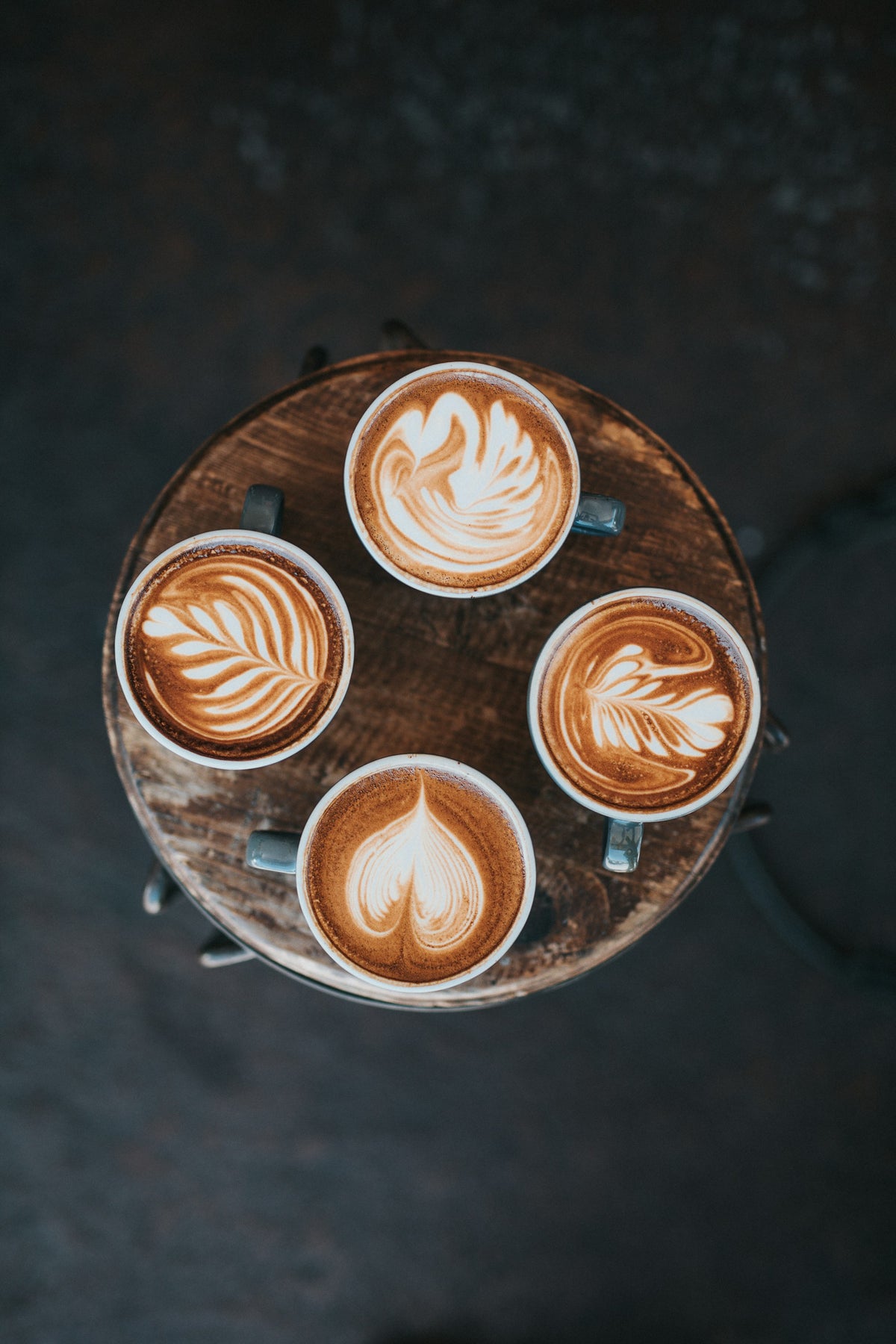 Quatre cafés latte art sur un plateau en bois